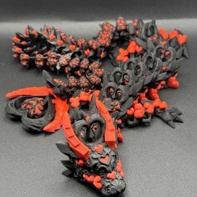 Escultura de dragão preta e vermelha com corações e chifres em fundo preto