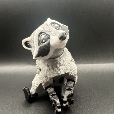 Boneco de guaxinim estilizado em material plástico cinza, branco e preto