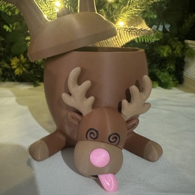 Caixa decorativa em forma de rena castanha com nariz rosa e língua cor-de-rosa
