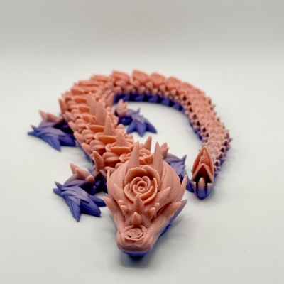 Escultura de dragão rosa com detalhes roxos e texto 'Arco-íris'