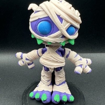 Figura de vinil de múmia roxa com faixas bege e unhas verdes