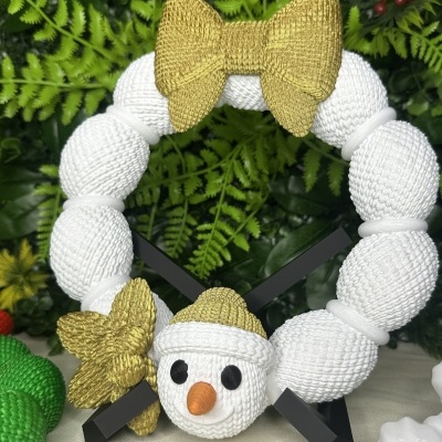 Guirlanda decorativa branca com laço dourado e rosto de boneco de neve em suporte