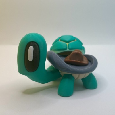 Figura de tartaruga azul esverdeada com carapaça verde e chapéu castanho