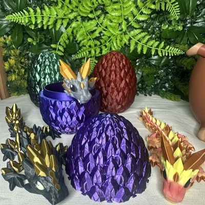 Figuras e ovos de dragão em plástico colorido sobre tecido branco com fundo de folhas artificiais