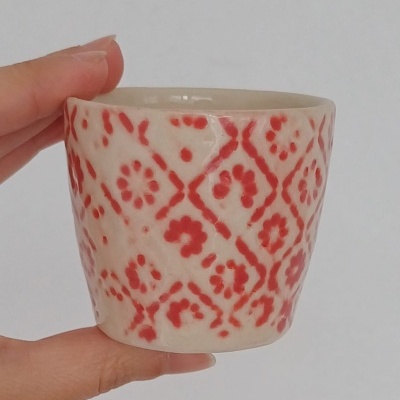 Vaso cerâmico com padrão vermelho e branco e textura brilhante