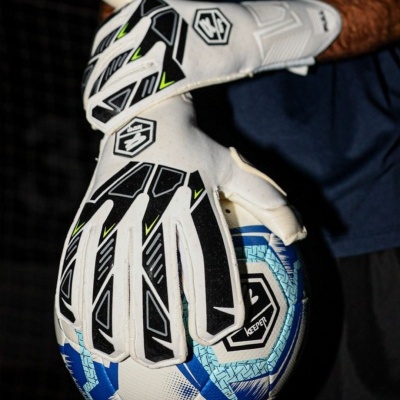 Luvas de guarda-redes a segurar bola de futebol azul e branca