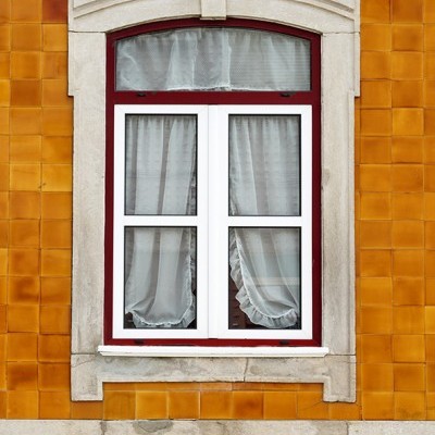 Janela com moldura de pedra e azulejos laranja na parede
