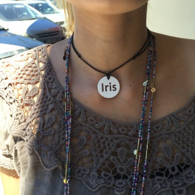 Colar com pendente branco escrito 'Iris' e blusa cinzenta bordada