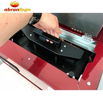 Máquina vermelha brilhante com peça preta metálica sendo segurada