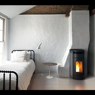 Quarto com cama metálica preta, a roupa de cama branca, luminária de pé, mesa lateral redonda e lareira moderna preta.