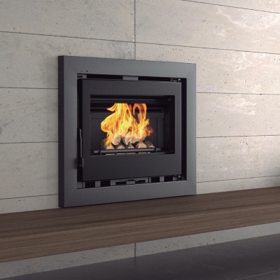 Recuperador de calor metálico cinza escuro com fogo visível instalado numa parede branca e prateleira de madeira