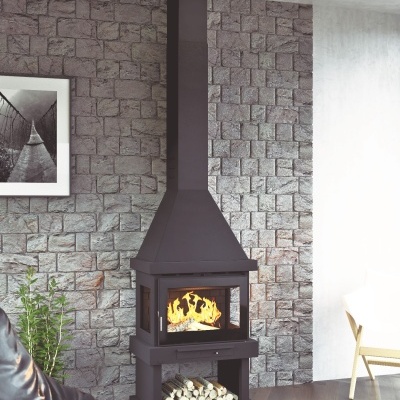 Lareira metálica negra com troncos secos contra parede de pedra cinzenta