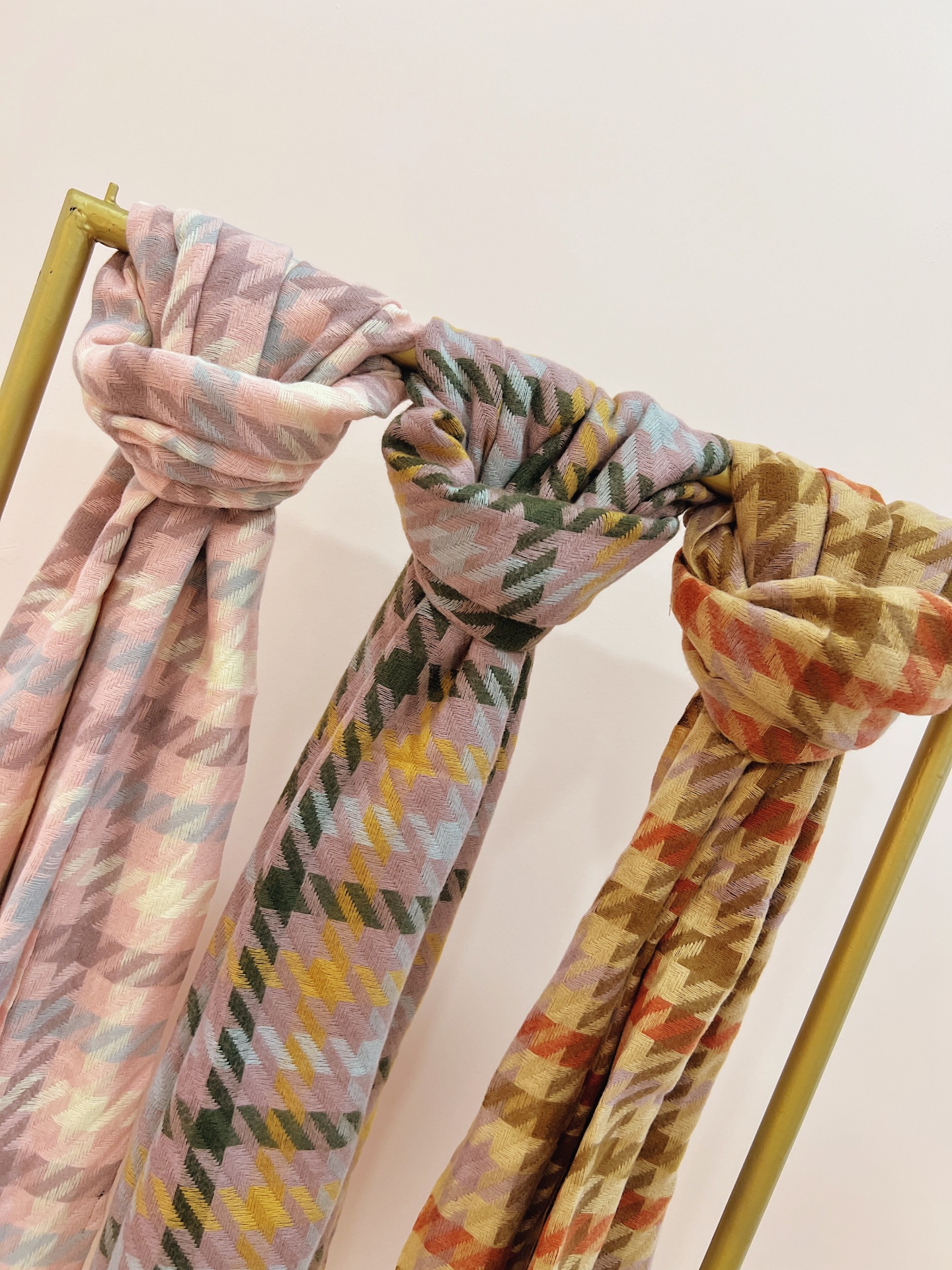 ECHARPE NATANAELA Três cachecóis com padrão geométrico pendurados