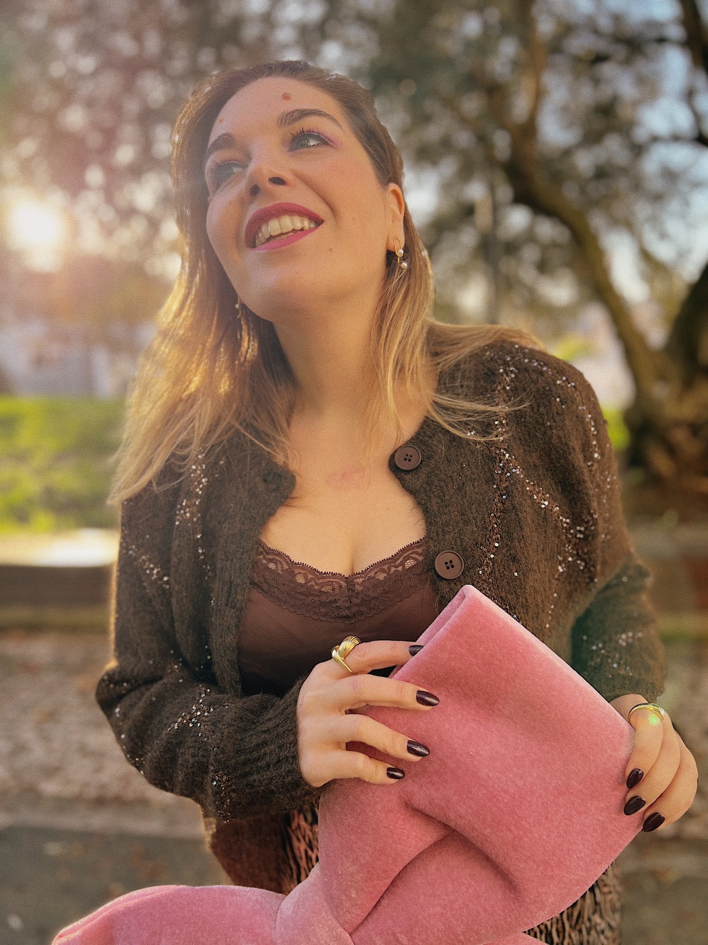 TOP TREFLE CASTANHO Mulher sorridente com camisola castanha e bota rosa felpuda ao ar livre.