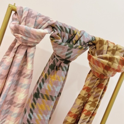 Três cachecóis com padrão geométrico pendurados