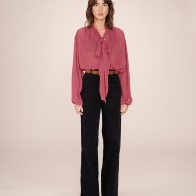 Mulher com blusa rosa e calças pretas