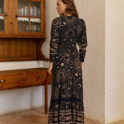 Vestido longo de manga comprida com padrão celeste e botas pretas em ambiente rústico