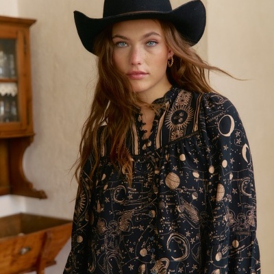 Camisa preta com padrão astronômico e chapéu preto em mulher