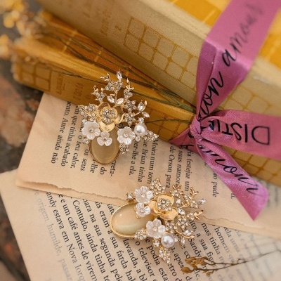 Brincos dourados com pedras e pérolas sobre livros e páginas de livro.