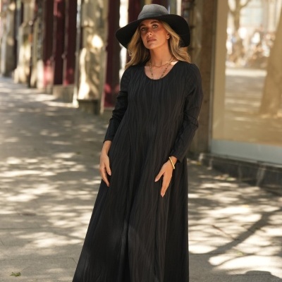 Vestido longo preto com padrão em relevo e chapéu preto de abas largas.
