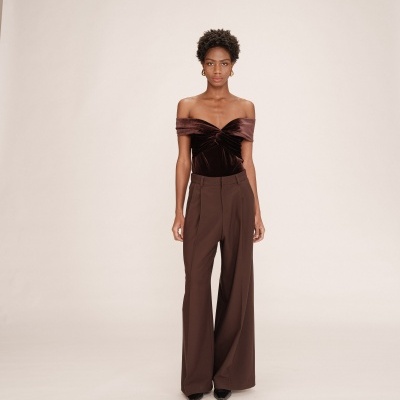 Mulher a usar blusa de veludo castanho e calças largas castanhas