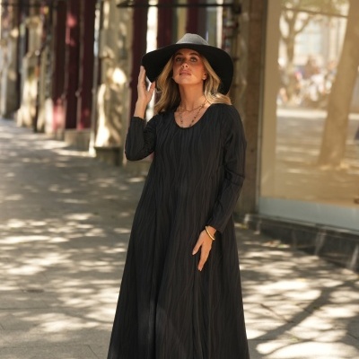 Mulher com vestido longo preto e chapéu preto num passeio urbano