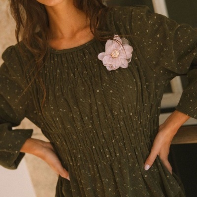 Vestido verde escuro com pequenos pontos claros e flor rosa com pérolas na parte superior.