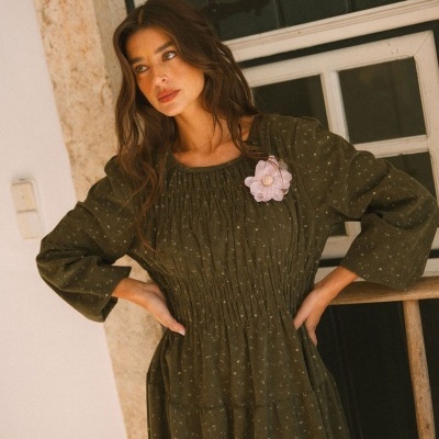 Vestido comprido verde escuro com padrão de flores pequenas brancas e flor rosa no peito