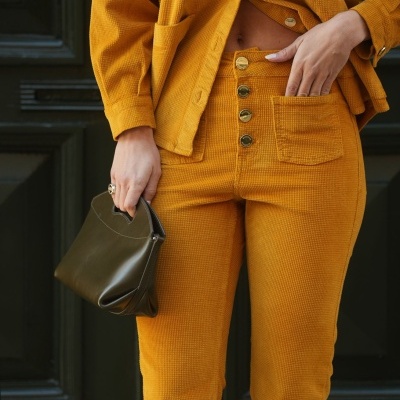 Conjunto amarelo mostarda com camisa e calças texturizadas e mala verde-oliva