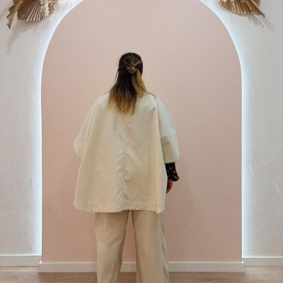 Pessoa de costas com roupa bege em arco com decoração de folhas secas