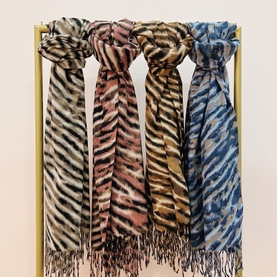 Quatro cachecóis com padrão de riscas em bege, rosa, castanho e azul pendurados num suporte amarelo