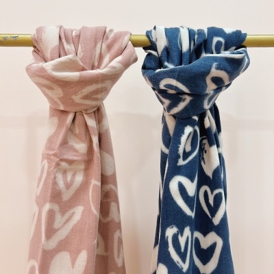 Dois cachecóis coloridos com padrão de corações pendurados num varão