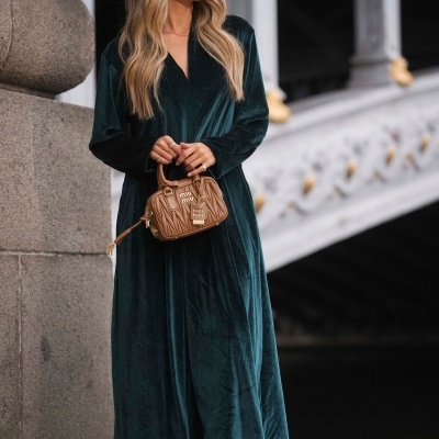 Mulher com vestido longo verde de veludo, mala castanha Miu Miu e botas castanhas ao ar livre