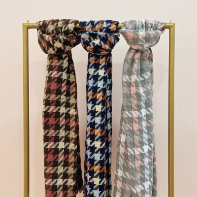 Três cachecóis pendurados com padrão pied de poule em três cores