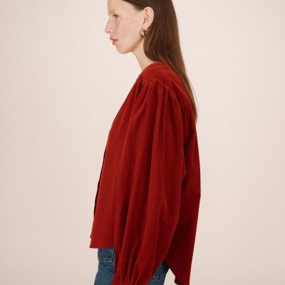 Blusa vermelha de veludo cotelê com mangas compridas e bufantes, vista de perfil