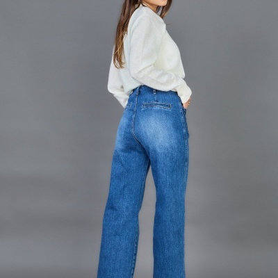 Mulher com camisola branca e calças de ganga azuis.