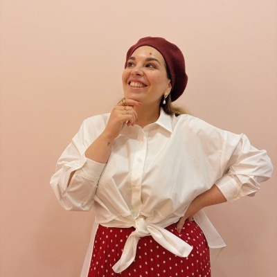 Mulher com roupa elegante e boina num fundo rosa.