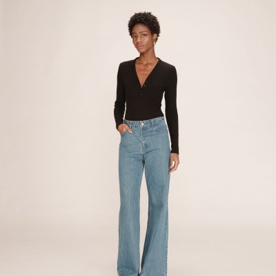 Mulher com camisola preta de malha e calças de ganga largas azul claro