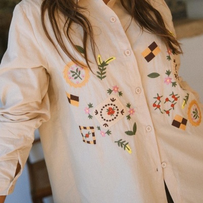 Camisa bege com bordados coloridos de flores e padrões geométricos