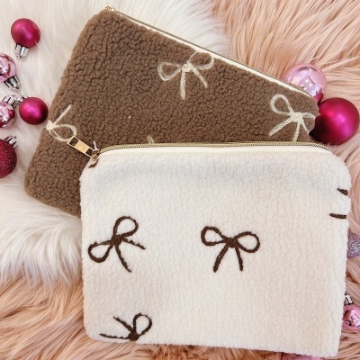 Duas bolsas de mão em pelúcia com estampado de laços e bolas de Natal ao redor