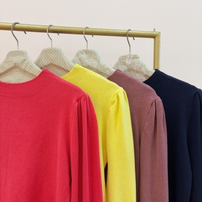 Camisolas de malha coloridas penduradas em cabides decorados sobre cabide metálico dourado