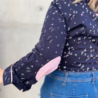 blusa azul escura com padrão de aviões de papel pequenos e cotoveleiras rosas