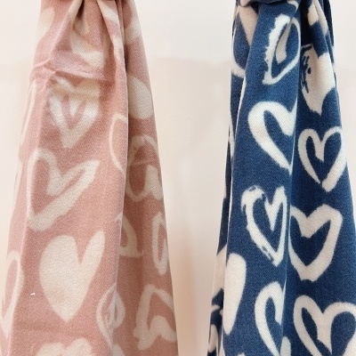 Dois cachecóis com padrão de corações em rosa e azul pendurados
