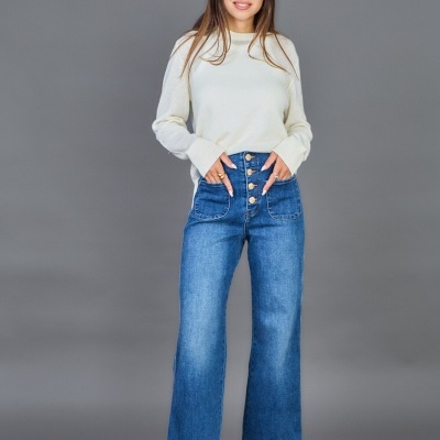 Mulher com camisola branca, calças ganga azuis e sapatos vermelhos