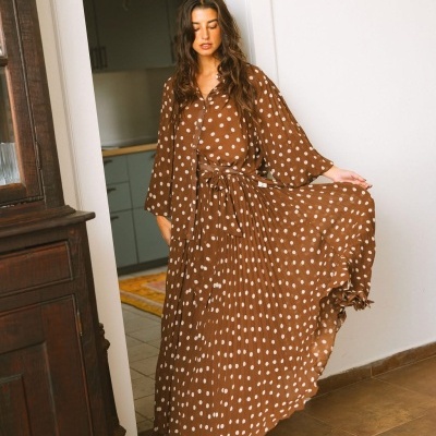 Vestido castanho com bolinhas brancas e cinto, usado em ambiente interior