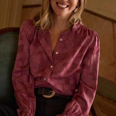 Blusa rosa com padrão floral e botões, usada por mulher sentada