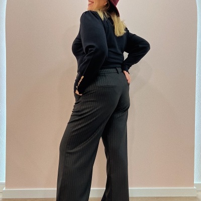 Mulher com roupa preta e chapéu vinho posando de costas