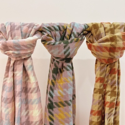 Três lenços grossos com padrão geométrico e variadas cores pendurados.