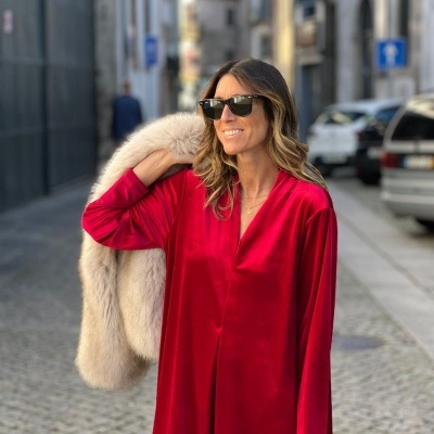 Mulher com vestido vermelho de veludo e casaco de pele bege sobre o ombro