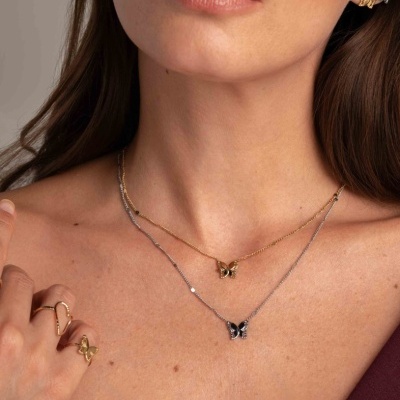 Colar duplo, brincos e anéis com pendentes de borboleta em mulher